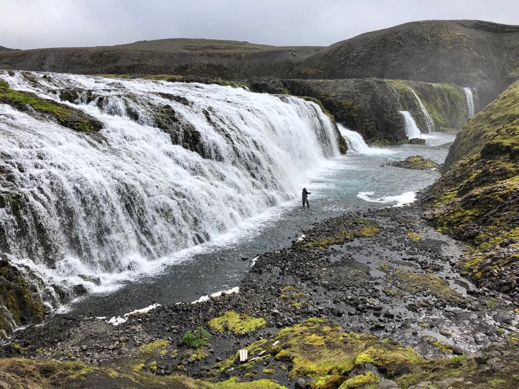 fisherman under icelandic waterfall